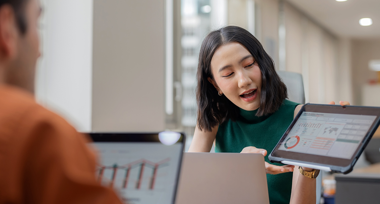 Female and male coworkers showing each other data on a tablet