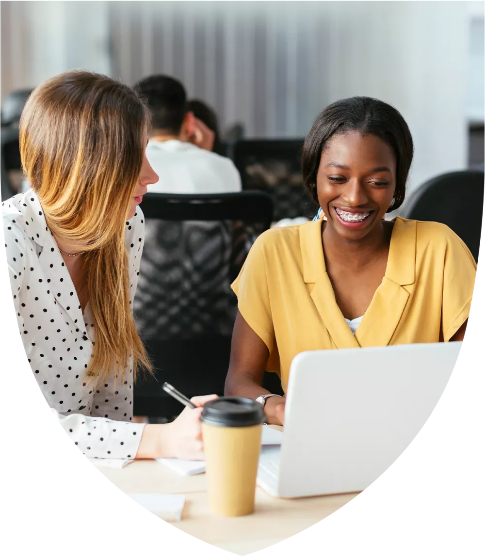 Two women talking while looking at a laptop