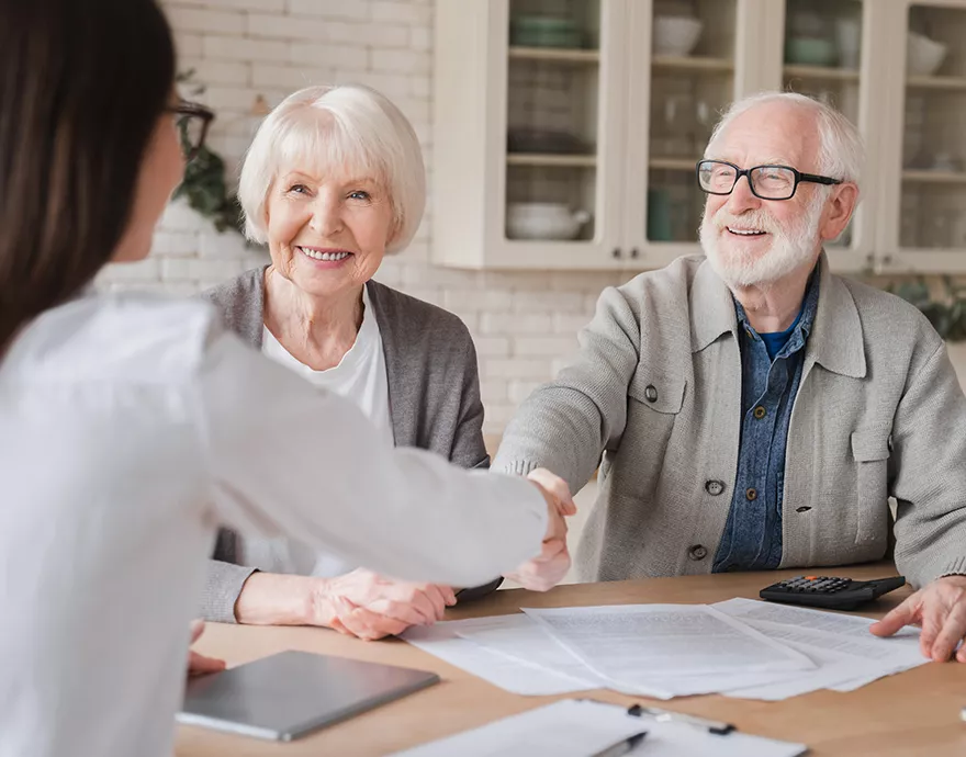 An elderly couple talking to a woman across a table