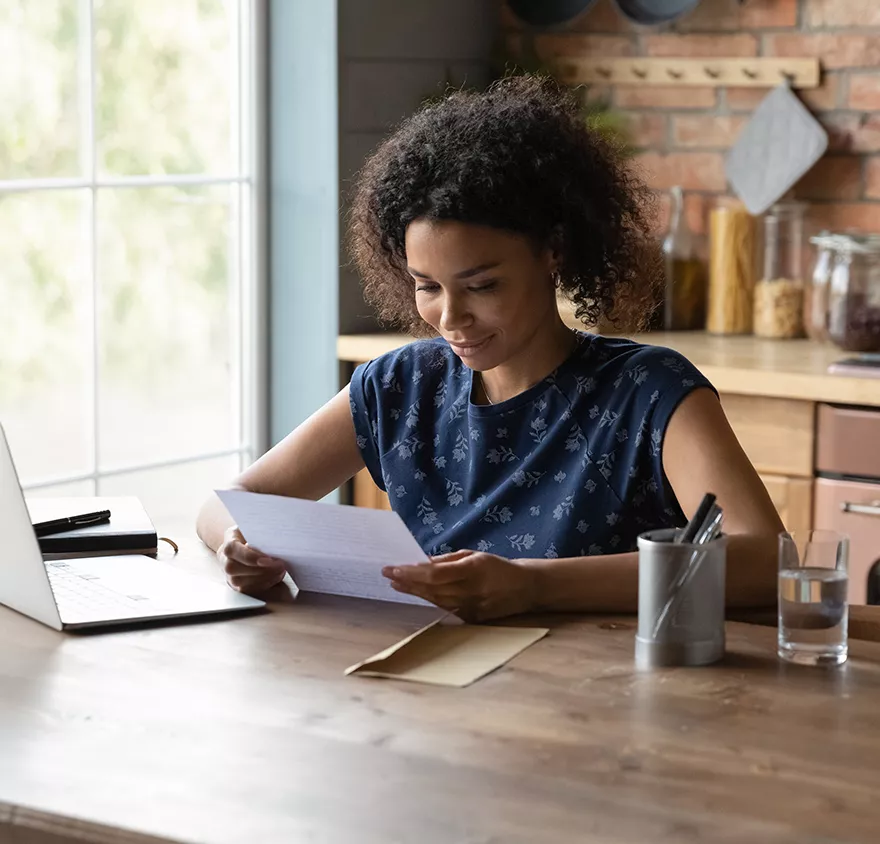 A woman reading an envelope at a table