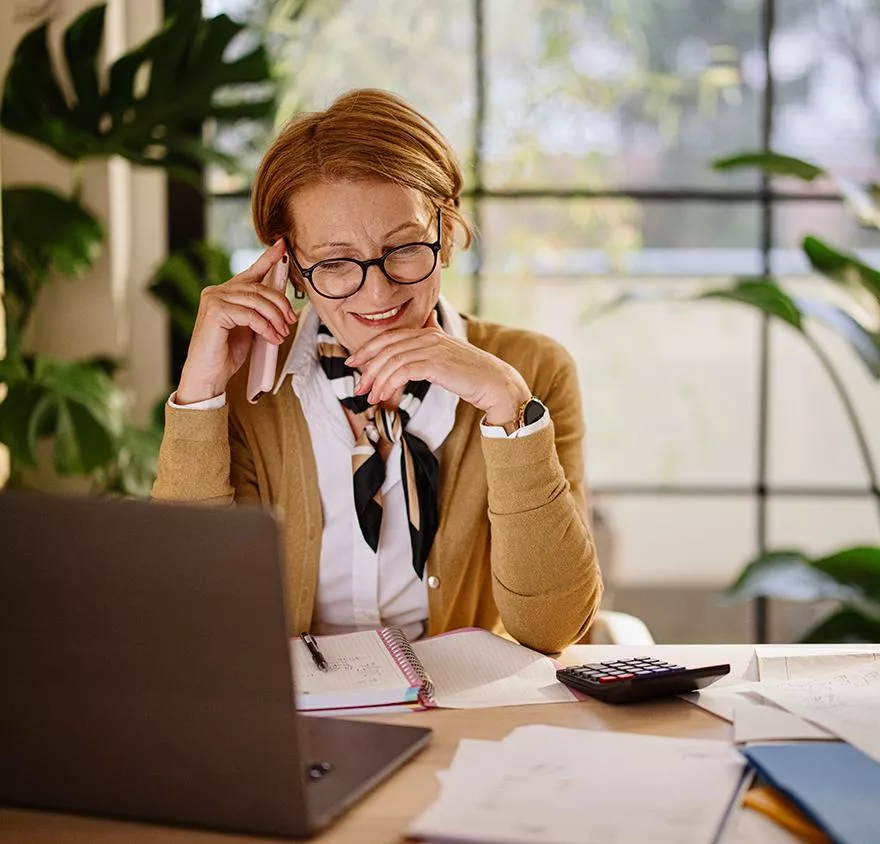 Woman talking on a cell phone and looking at a laptop