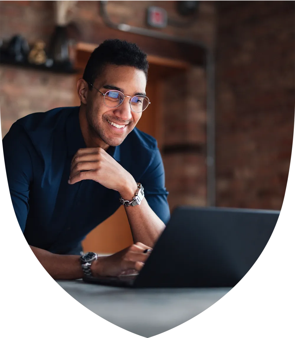 Man in his late 30's smiling while studying for an exam on his laptop