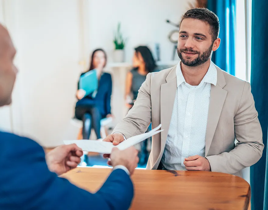Man in a suit handing in his resume for a job