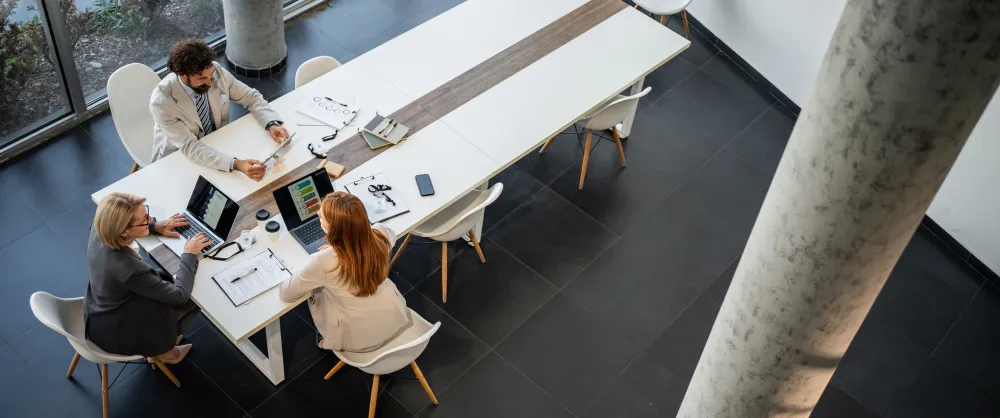 Group of three coworkers sitting together at a long table