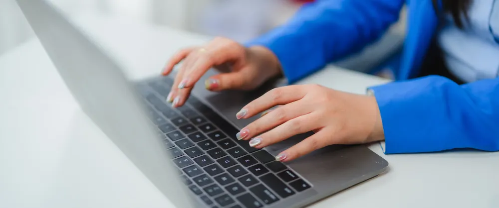 Woman wearing blue shirt typing on her laptop