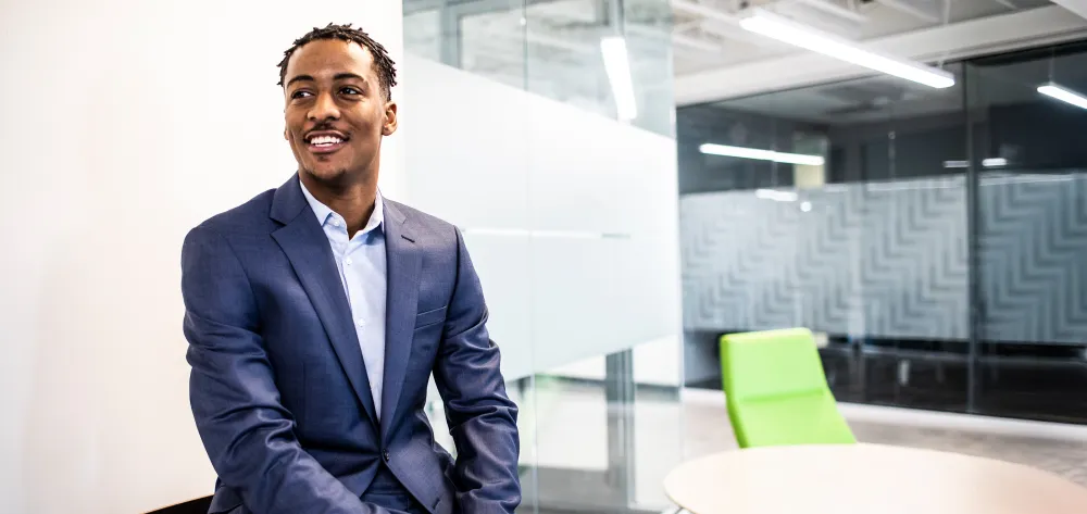 Young male professional smiling while sitting on his desk