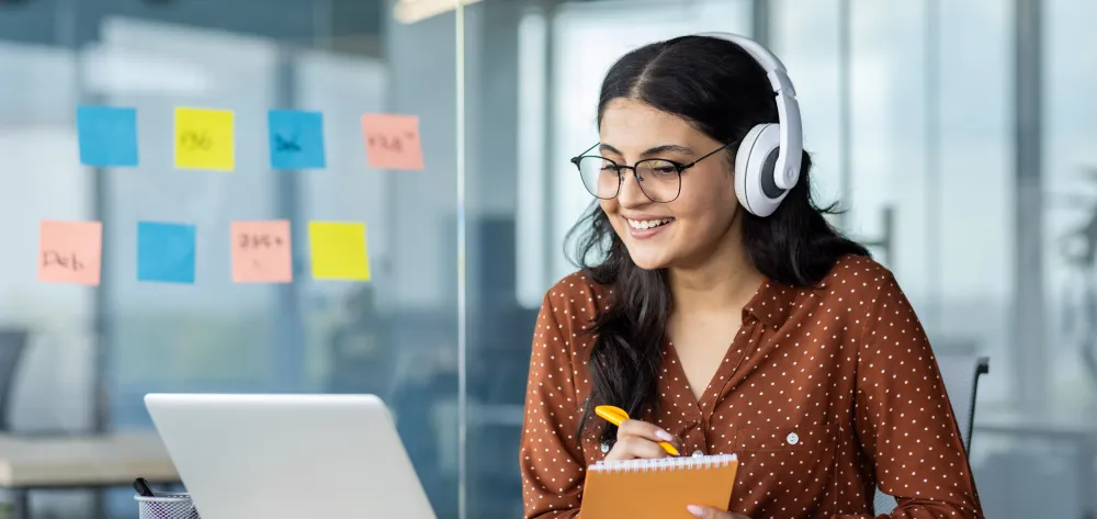Woman wearing headphones while working at her desk