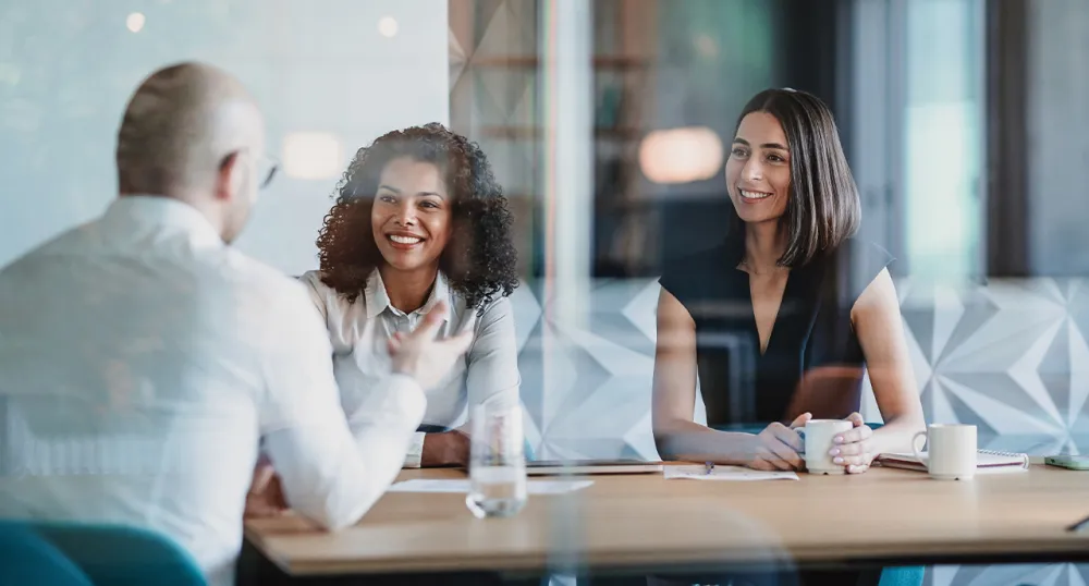 Two women speaking with another man in the office