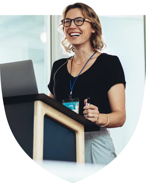 Happy businesswoman standing at the podium presenting to crowd