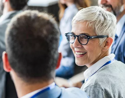 Two colleagues smiling and talking together at a conference