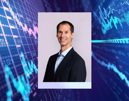 Photo of Eric Ludwig with stock market graphs behind him