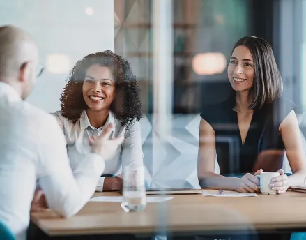 Two women speaking with another man in the office